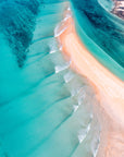 Aerial view of a beach with turquoise water and red sand, likely in the Pilbara region of Australia.