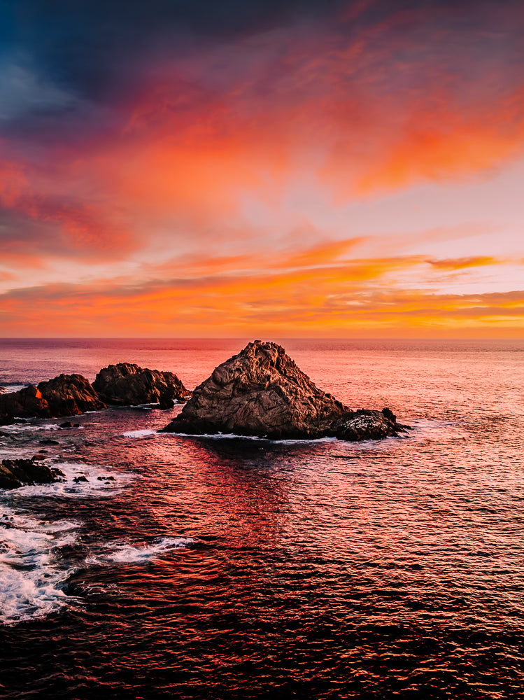Aerial sunset photograph of Sugarloaf Rock, South West Western Australia, with deep orange and pink sky reflecting on the ocean.